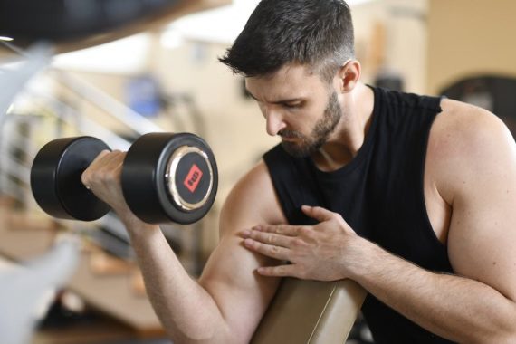 Focused man lifting dumbbell, showcasing strength and fitness indoors.
